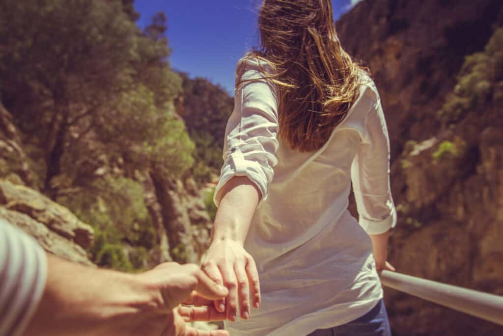 Eine Frau hält die Hand einer weiteren Person und führt sie voran.